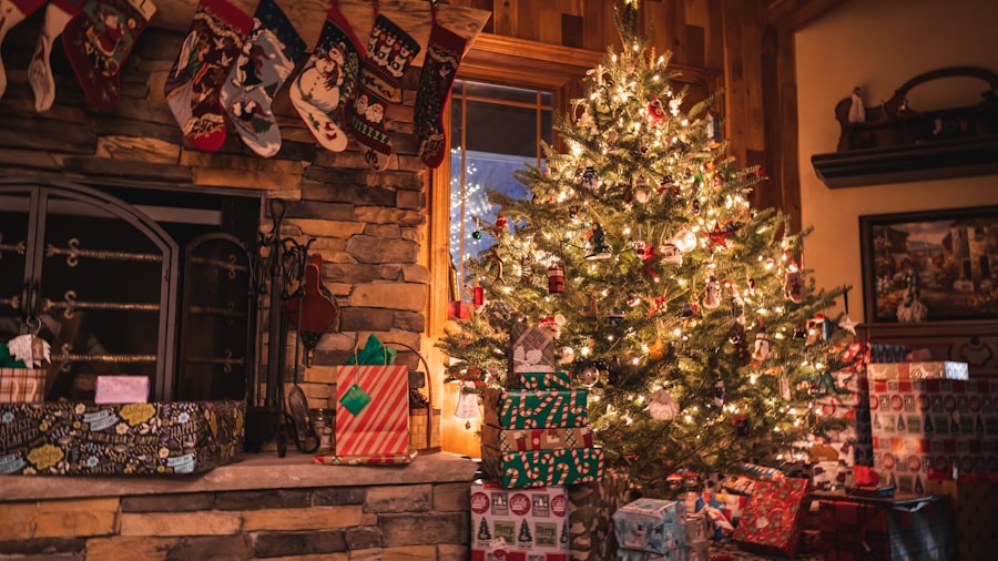 warmly lit Christmas tree covered in ornaments with wrapped gifts underneath, next to a rustic stone fireplace