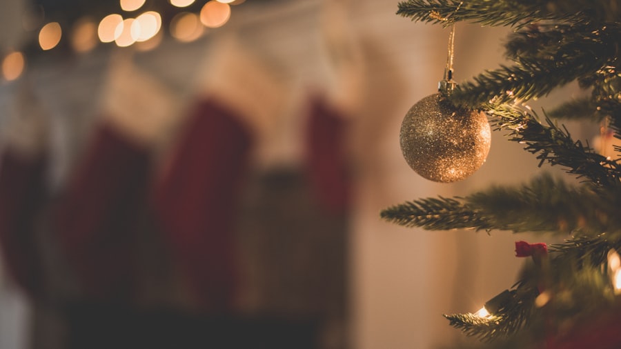 close-up of a gold ornament on a Christmas tree with soft glowing bokeh lights and stockings blurred behind