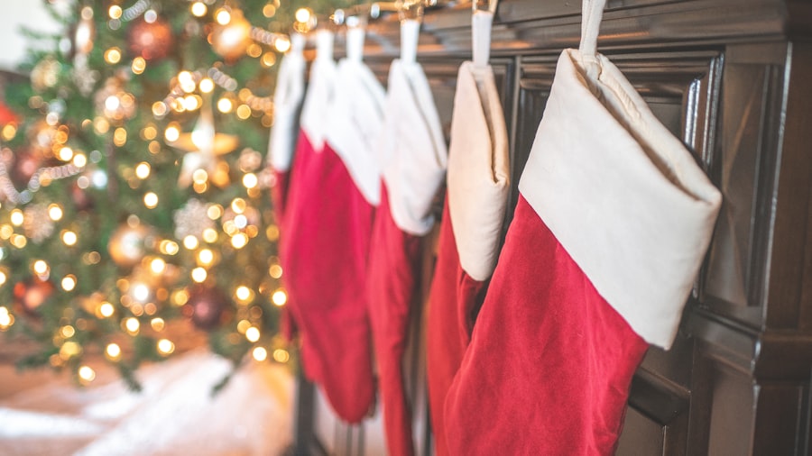 red and white stockings hung on a mantel with a softly glowing Christmas tree behind
