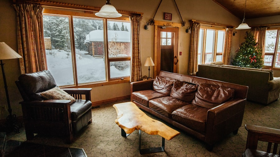 log cabin living room with leather sofas, a decorated Christmas tree, and snow-covered pines through the windows