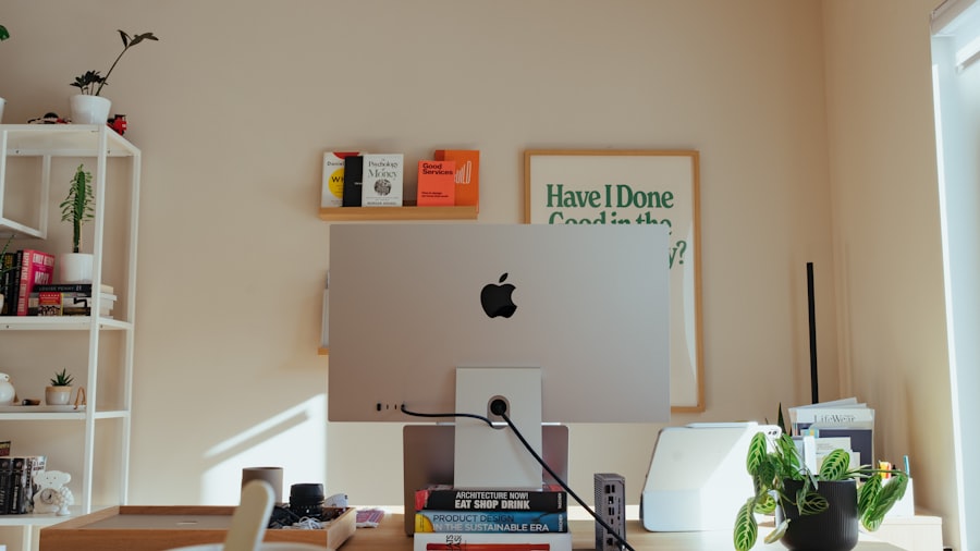 bright home office desk with an iMac, framed posters, and small potted plants by a window