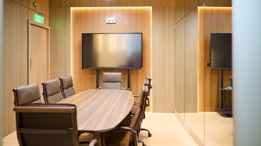 modern wood-panelled meeting room with a long table, black chairs, and a wall-mounted screen