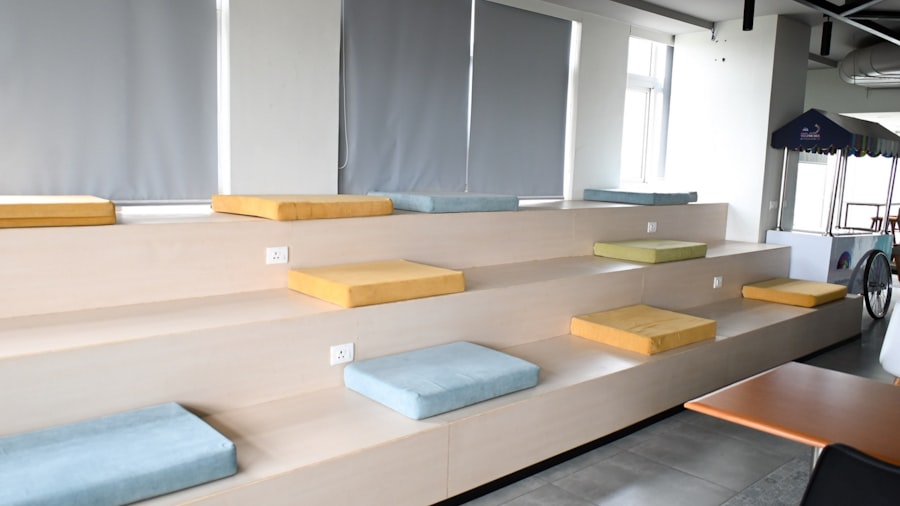 bright coworking lounge with tiered wooden bench seating and cushions beside tall windows