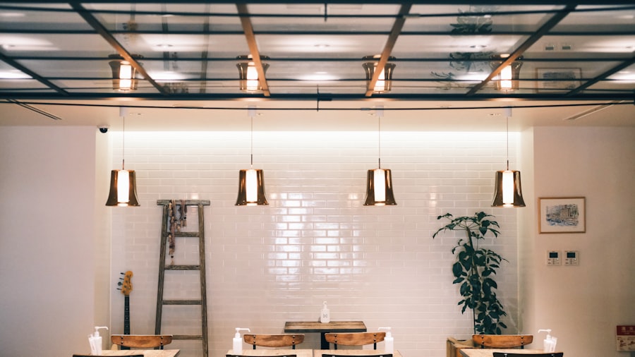 bright white café with brass pendant lights, a plant, and a softly blurred back wall